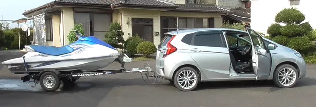 住宅前で乗用車がジェットスキーを牽引している様子