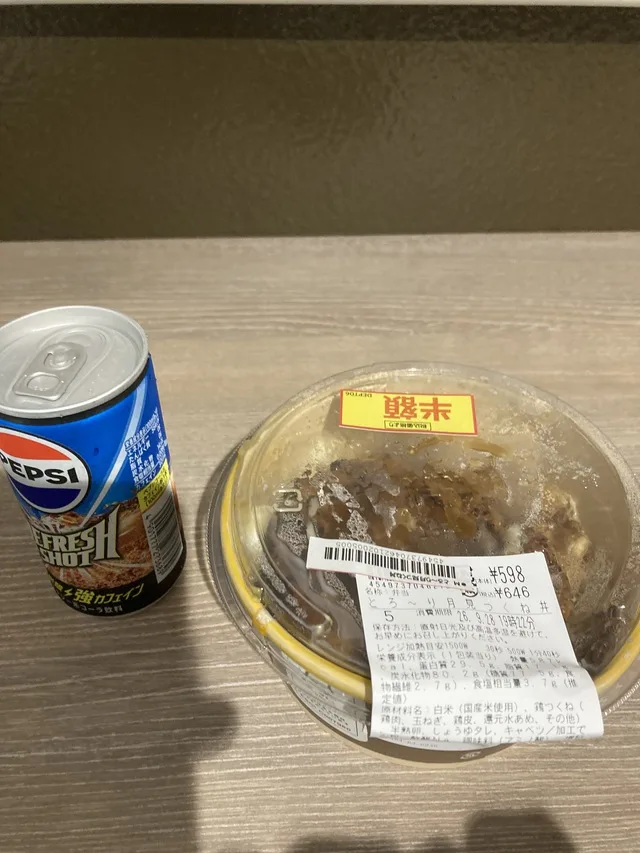 テーブルの上に置かれた弁当とペプシの缶