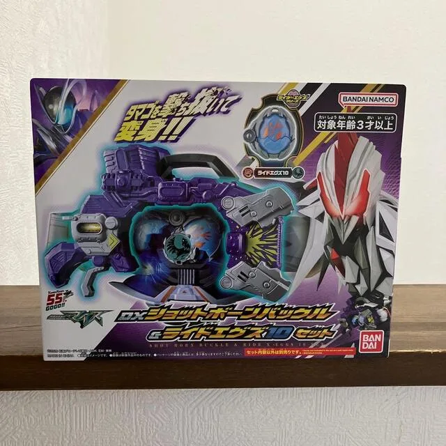紫や銀色の変身玩具の箱。赤い目のキャラクターと玩具本体が描かれている。
