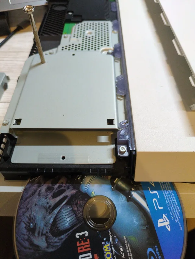 分解されたゲーム機本体とネジ回し、ゲームディスク