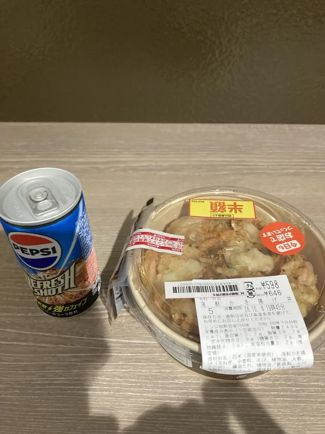 テーブルに置かれたペプシの缶と、鶏肉が入った惣菜の容器