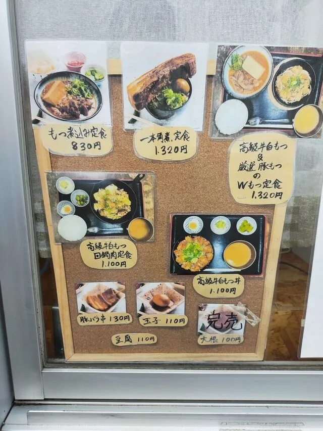 飲食店の料理写真と手書きの定食メニューが並んだ店頭の案内板
