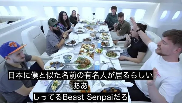 飛行機内のテーブルを囲んで食事をする男女と、日本語字幕
