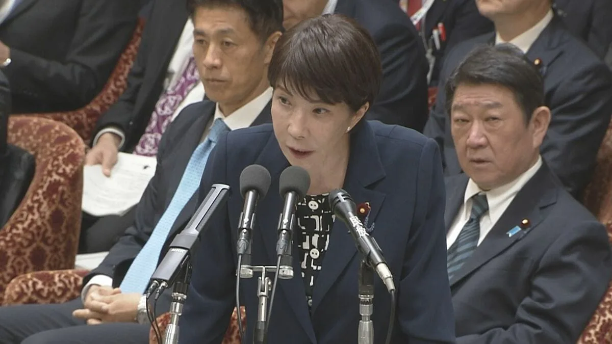 国会の委員会で、女性議員が複数のマイクの前で発言している