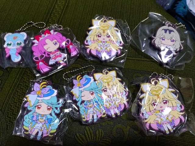 布の上に並べられた、魔法少女風のキャラクターが描かれたキーホルダー