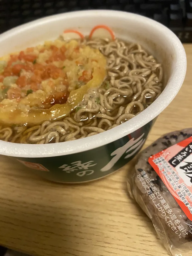 天ぷらがのったカップそばと、隣に置かれた商品の包装
