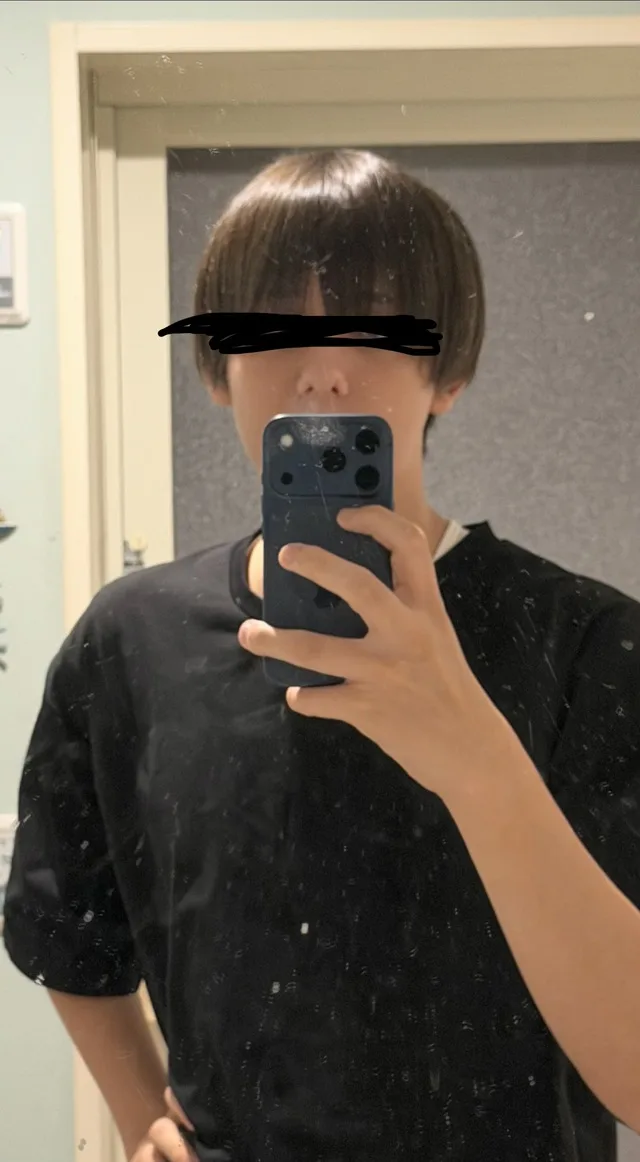 黒いTシャツを着た人物がスマートフォンで鏡越しに撮影した自撮り写真