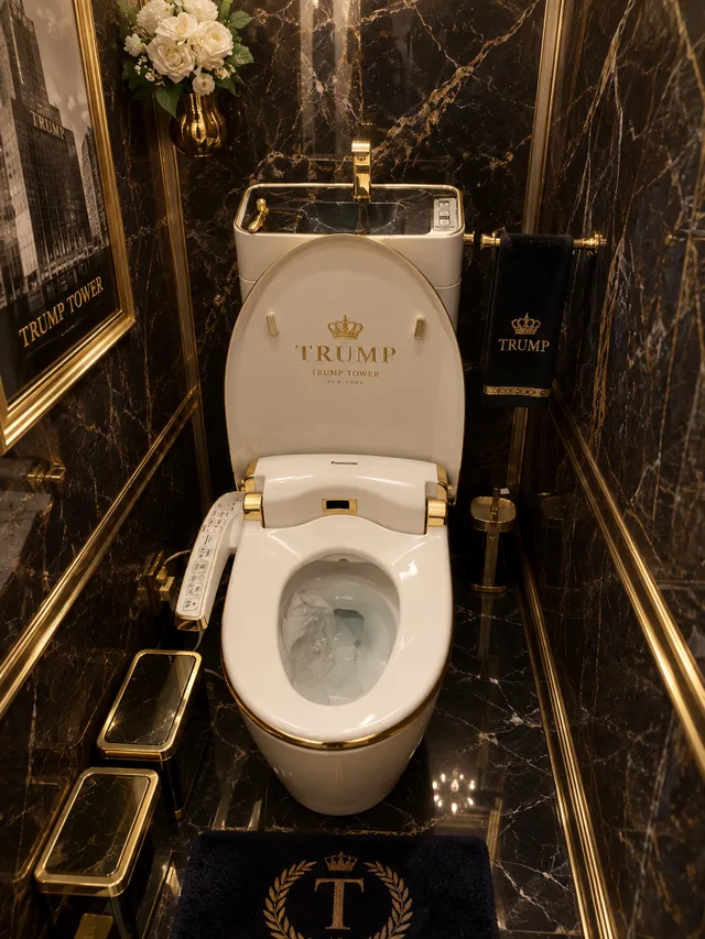 黒い大理石の壁に囲まれた、金色の装飾があるトランプタワーのトイレ。