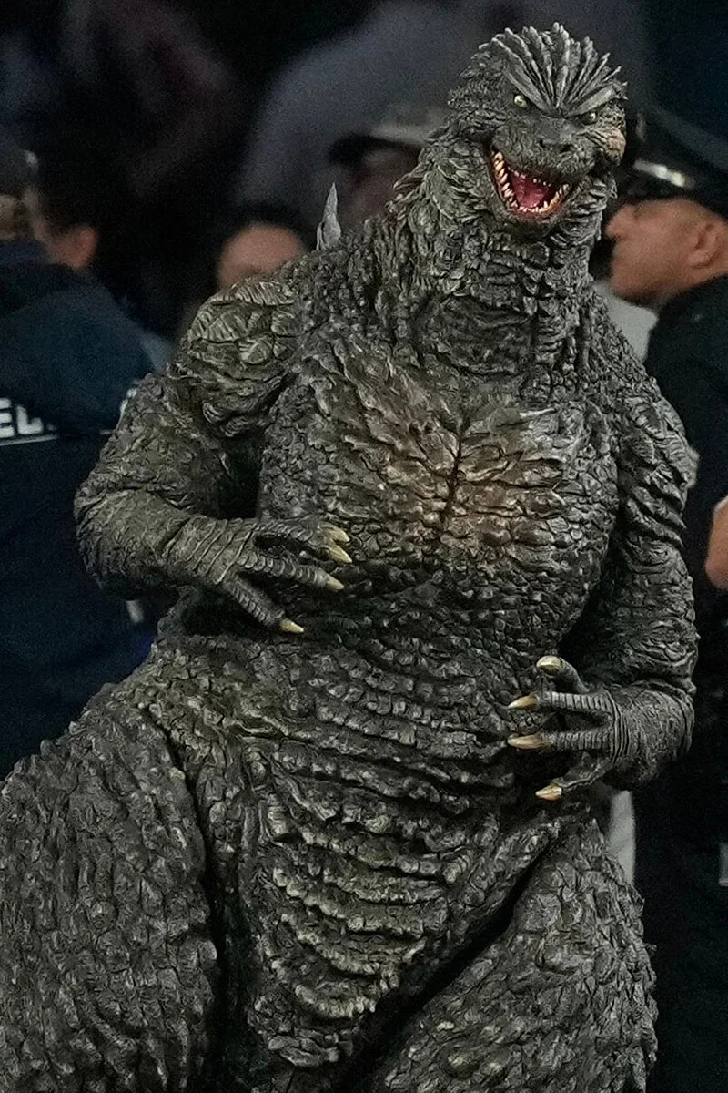 観客の前で口を開けるゴジラの着ぐるみ姿。