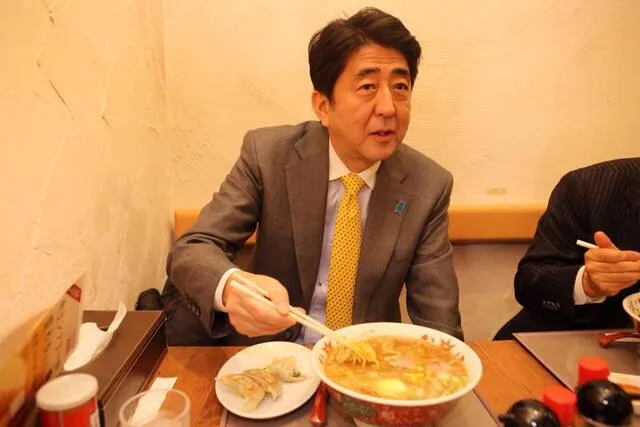 スーツ姿の男性が食卓で鍋料理を食べている