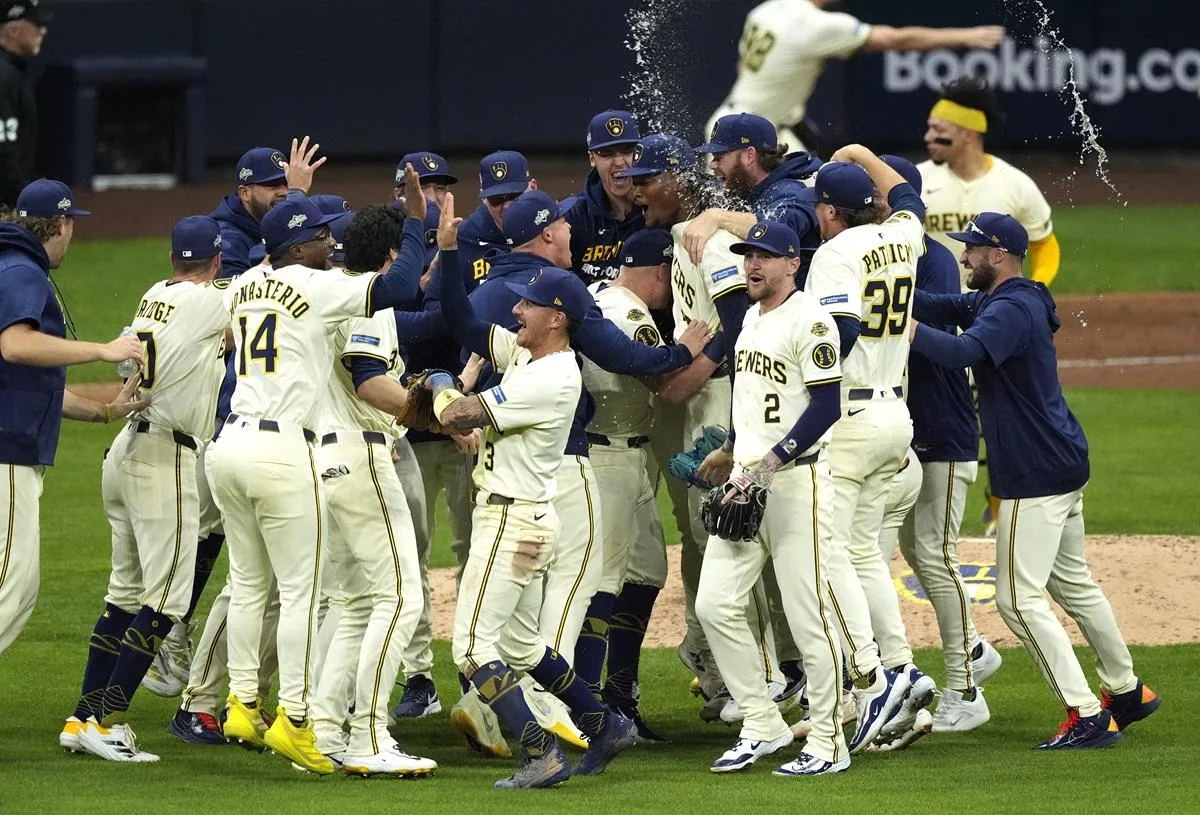 白いユニフォームの野球選手たちが、グラウンドで輪になって喜んでいる。