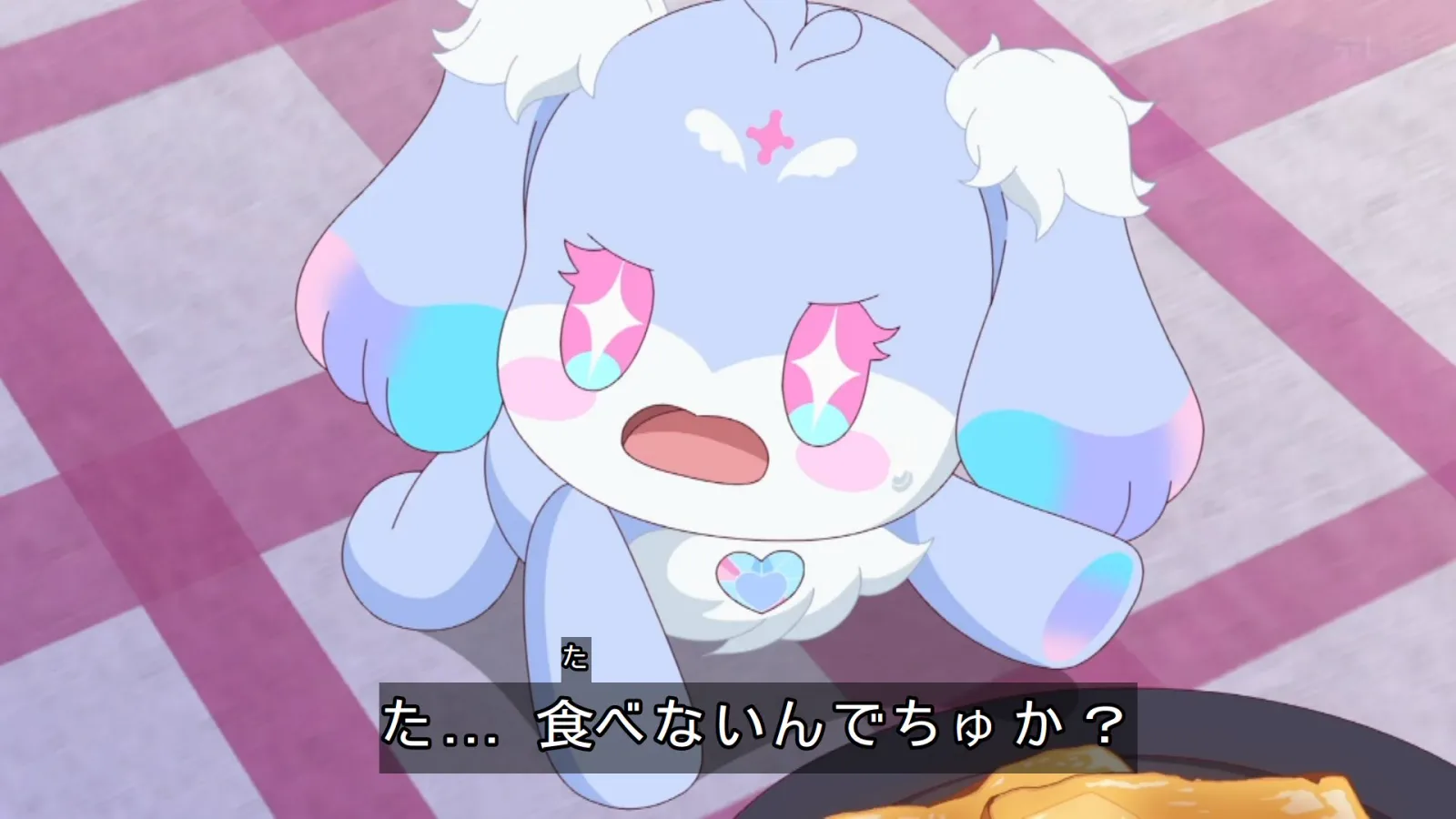 パステルカラーのウサギのようなキャラクターが、驚いた表情で食べ物を見下ろしているアニメ場面。