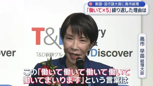マイクの前で話す女性。背景に企業ロゴ、画面上部と下部に字幕がある。