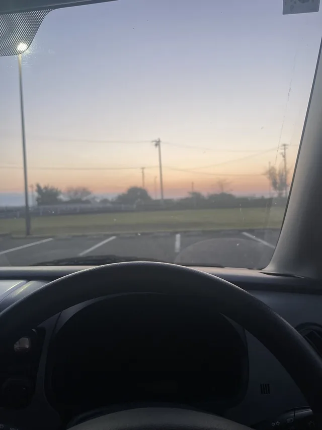 車内から見た、夕焼けの駐車場と遠くの電柱。