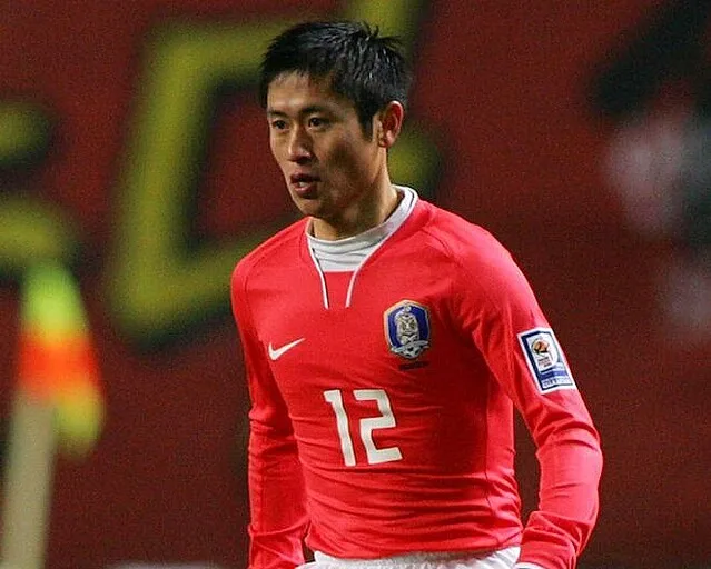 赤い背番号12のサッカー代表ユニフォームを着た男性選手