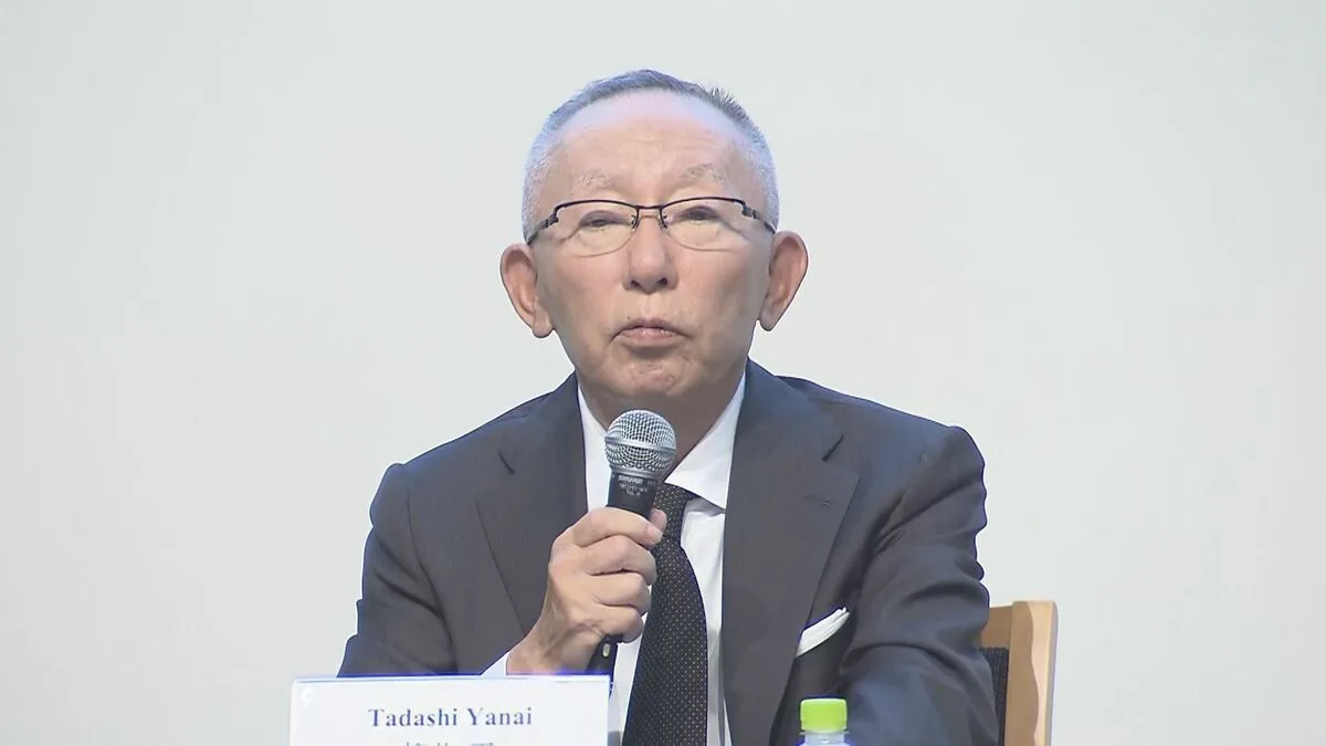 スーツ姿の男性がマイクを持って話している。